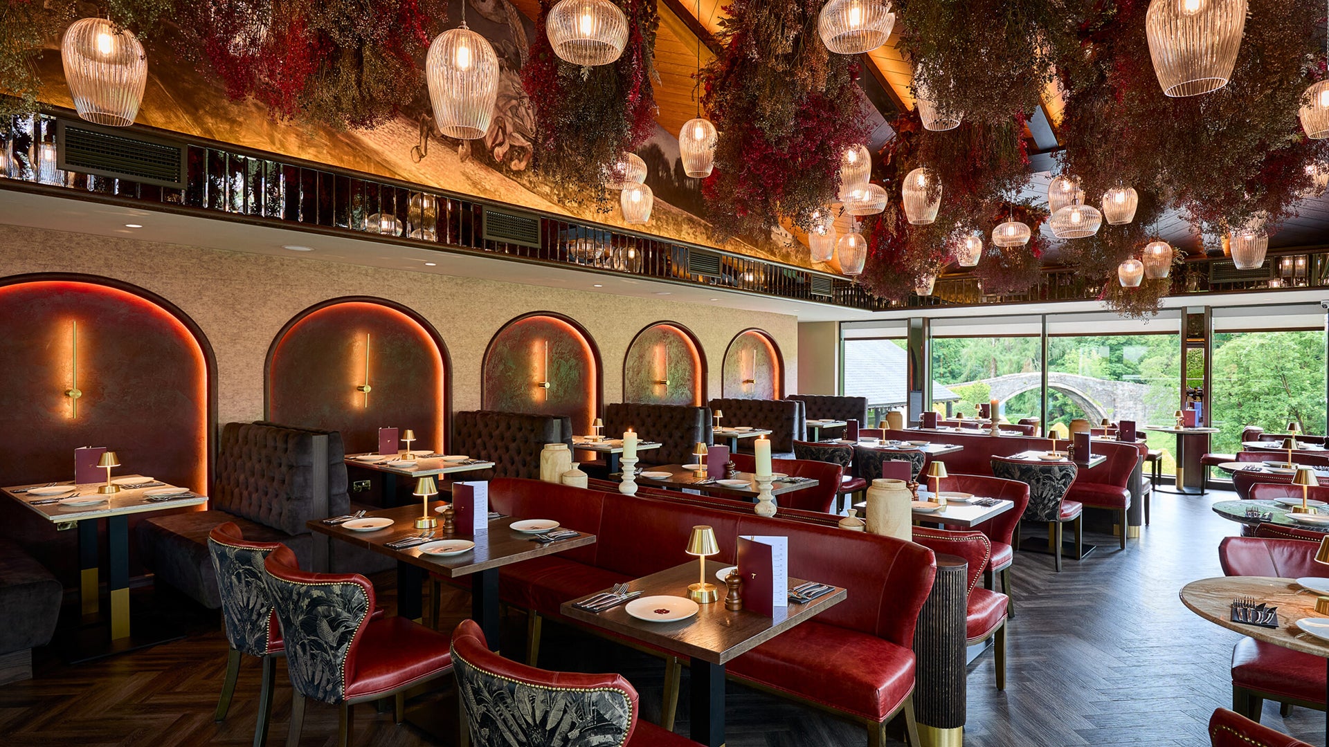 Interior of a stylish restaurant with tables, small gold cordless table lamps, chairs, and decorative elements.