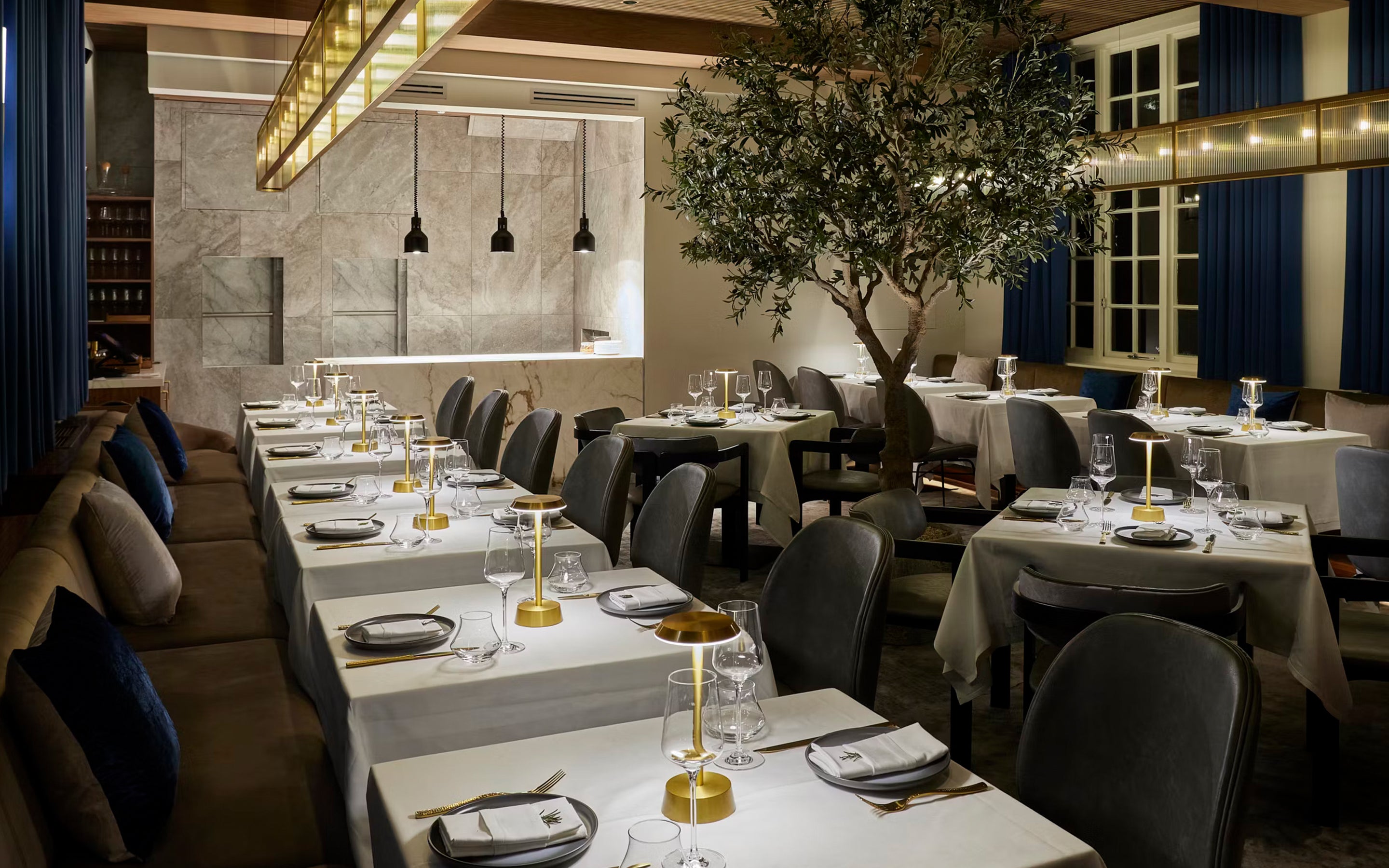 Modern restaurant interior with tables set for dining, chairs, and decorative elements.