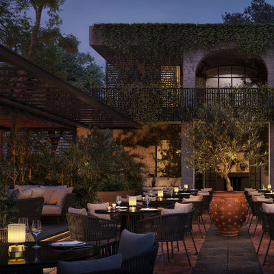 A collection of small rechargeable lamps illuminating outdoor dining tables at a high end terrace.  