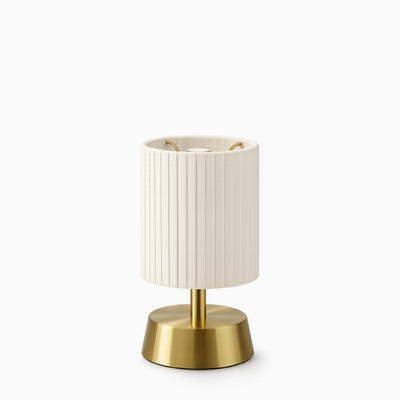 Cordless table lamp with ivory pleated shade and brass base on a white background