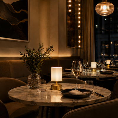 Dining table setting in a restaurant with wine glasses and a vase.