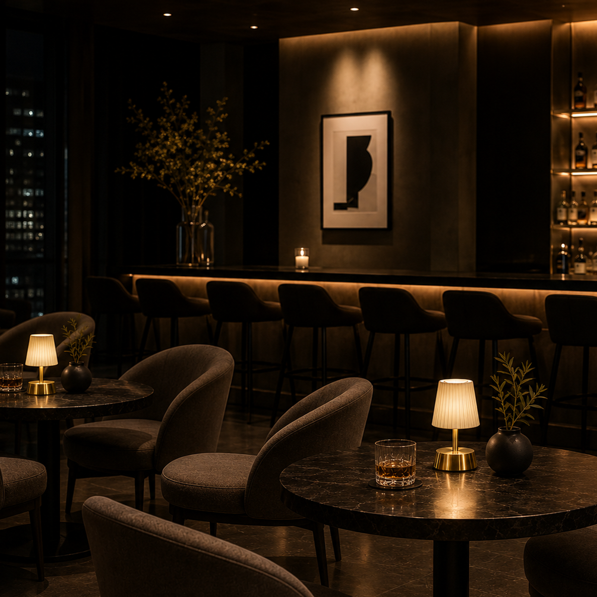 Dark and moody interior of a bar with cordless lamps, chairs, and tables.