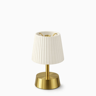 Cordless table lamp with ivory pleated shade and brass base on a white background