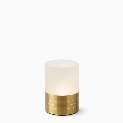 Small cylindrical cordless lamp with frosted shade and gold base on a white background