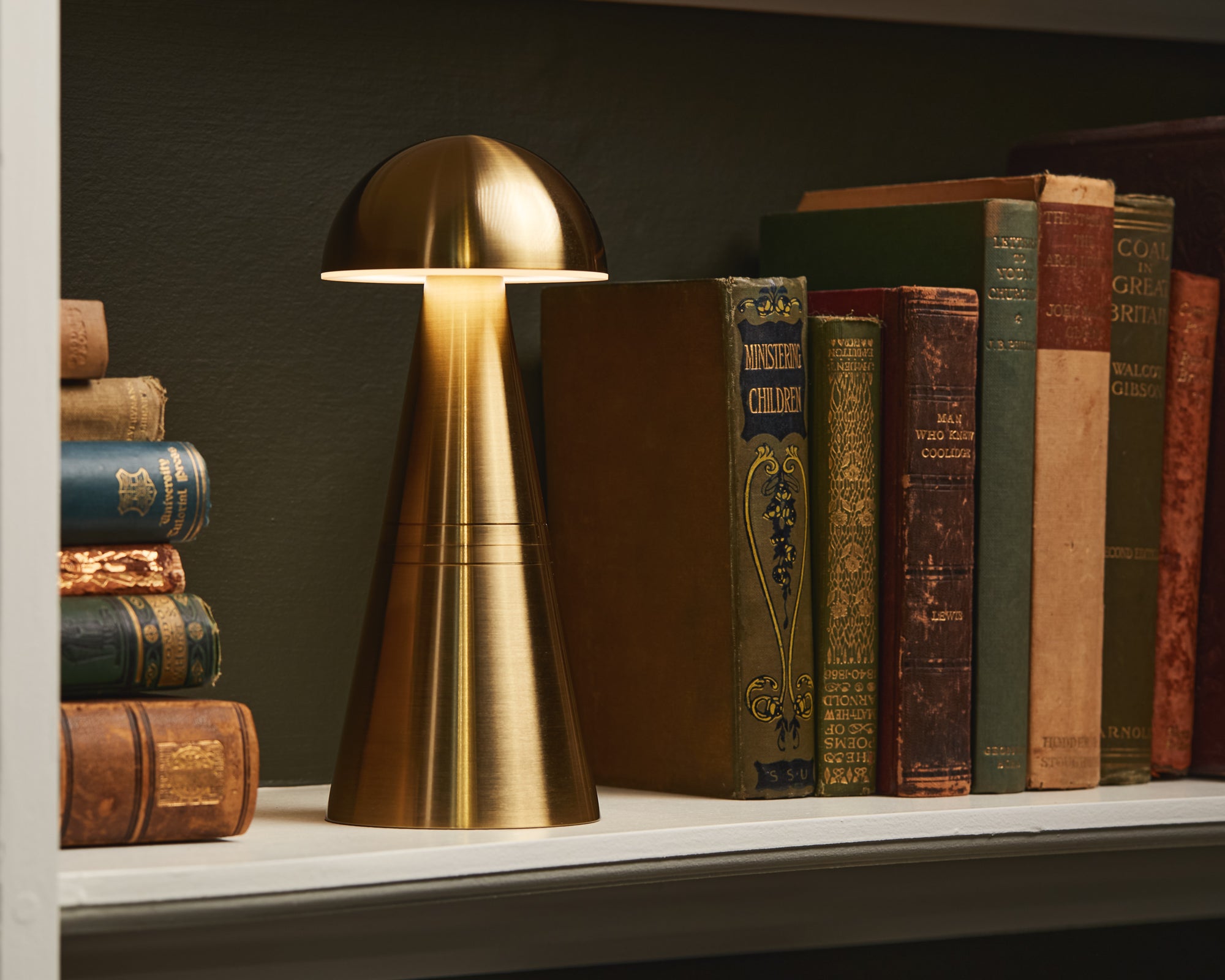 Brass cordless table lamp on a shelf with vintage books