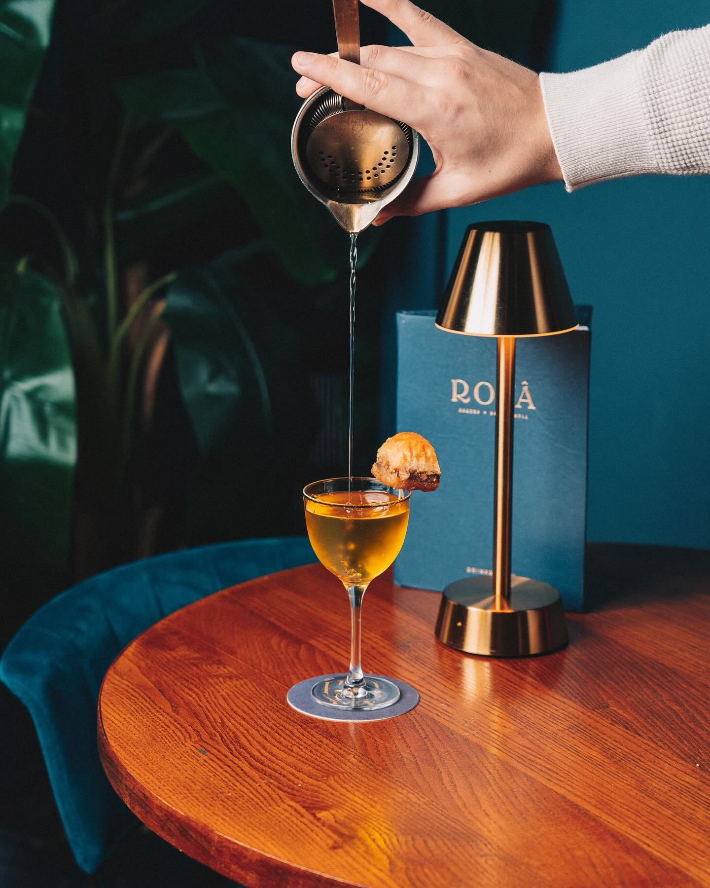 Cocktail being prepared with a rechargeable table lamp in the background.