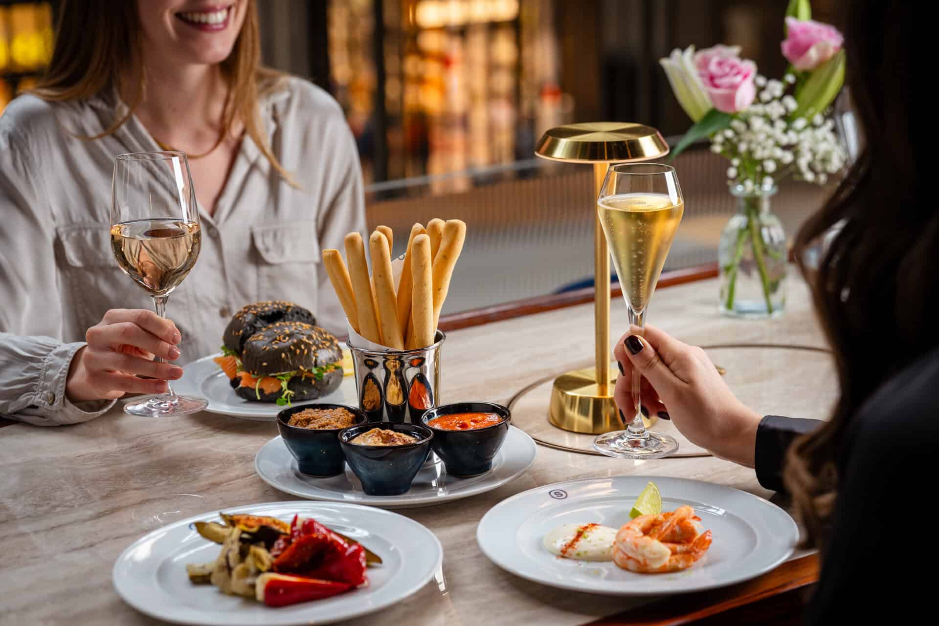 Two people enjoying a meal with wine and appetizers at a restaurant.