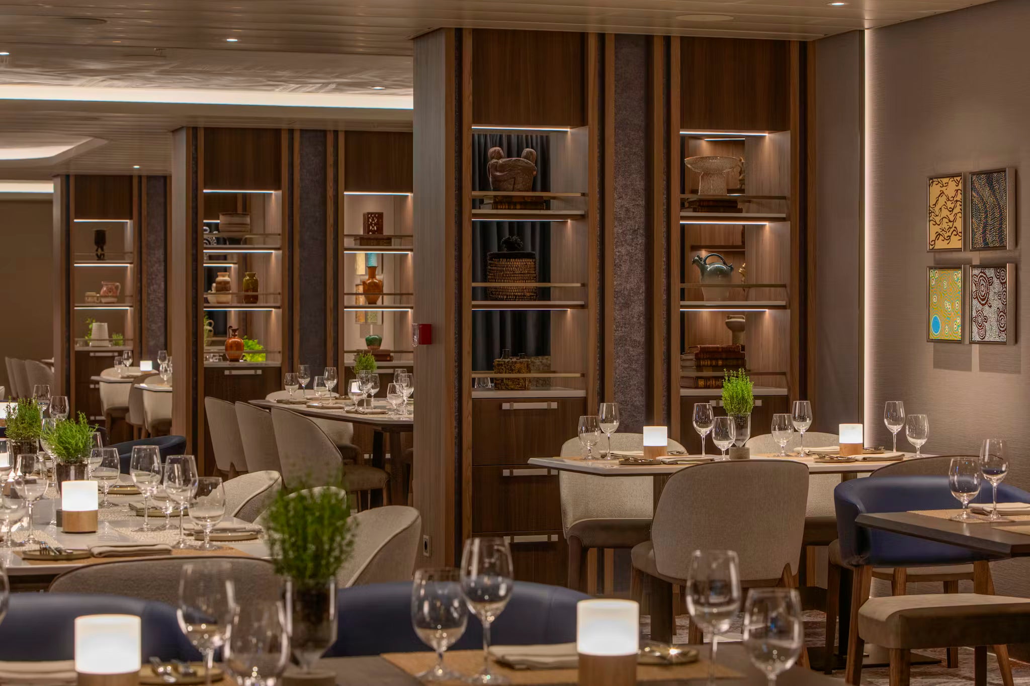 Elegant restaurant interior on a crusie ship with tables set for dining, wood cordless table lamps, wine glasses, and decorative elements.