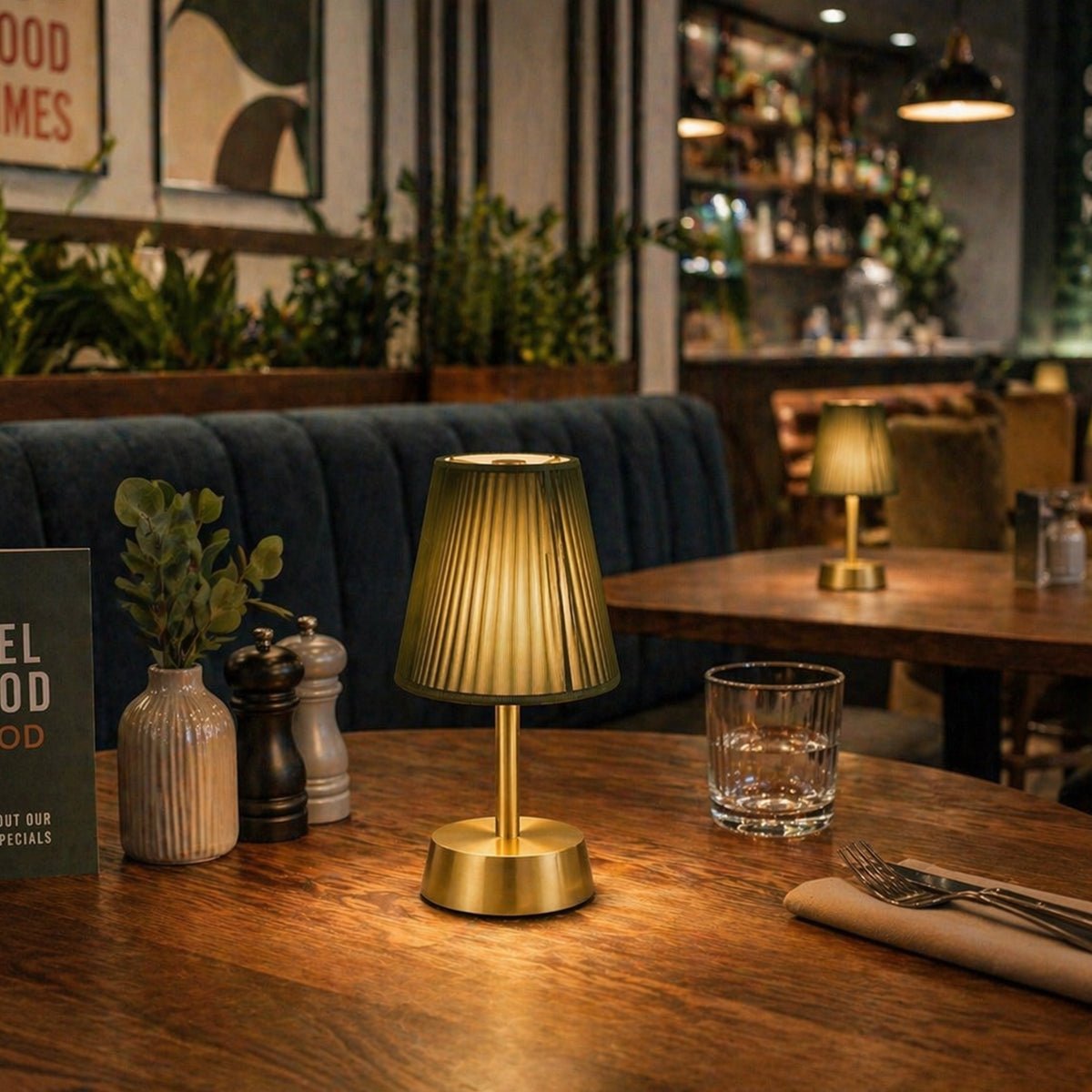 Gold rechargeable table lamp on a wooden table in a restaurant setting