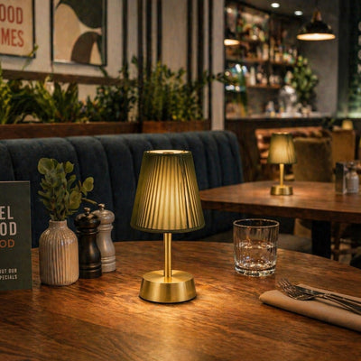 Gold rechargeable table lamp on a wooden table in a restaurant setting