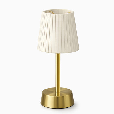 Cordless table lamp with ivory pleated shade and brass base on a white background