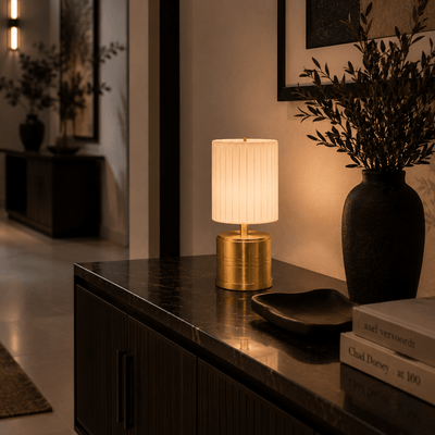 Decorative rechargeable lamp on a table with books and a vase in a softly lit room.