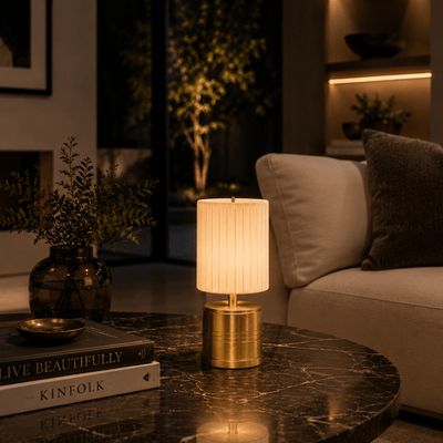 Decorative rechargeable lamp on a marble table with books and a plant in a dimly lit room.