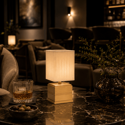 Decorative rechargeable lamp on a marble surface with a glass of whiskey and a bowl of snacks in a dimly lit room.