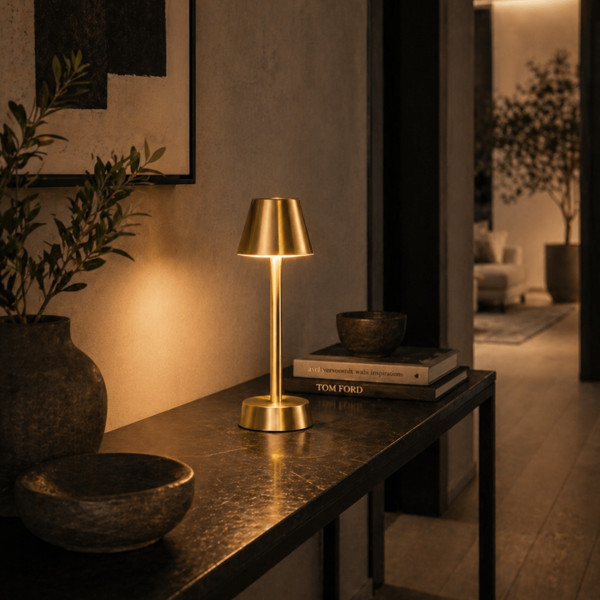 Brass rechargeable cordless table lamp on a dark surface with a blurred indoor setting