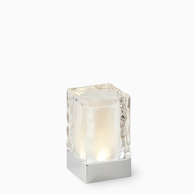Crystal-like glass cordless table lamp with a white light on a white background